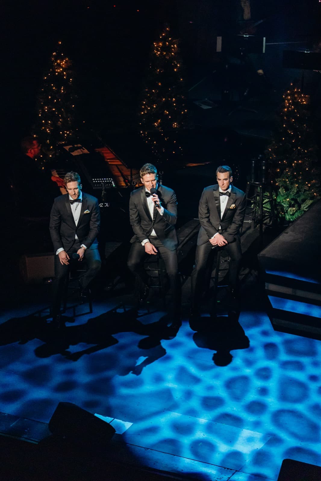 GENTRI vocalists performing under blue stage lighting.