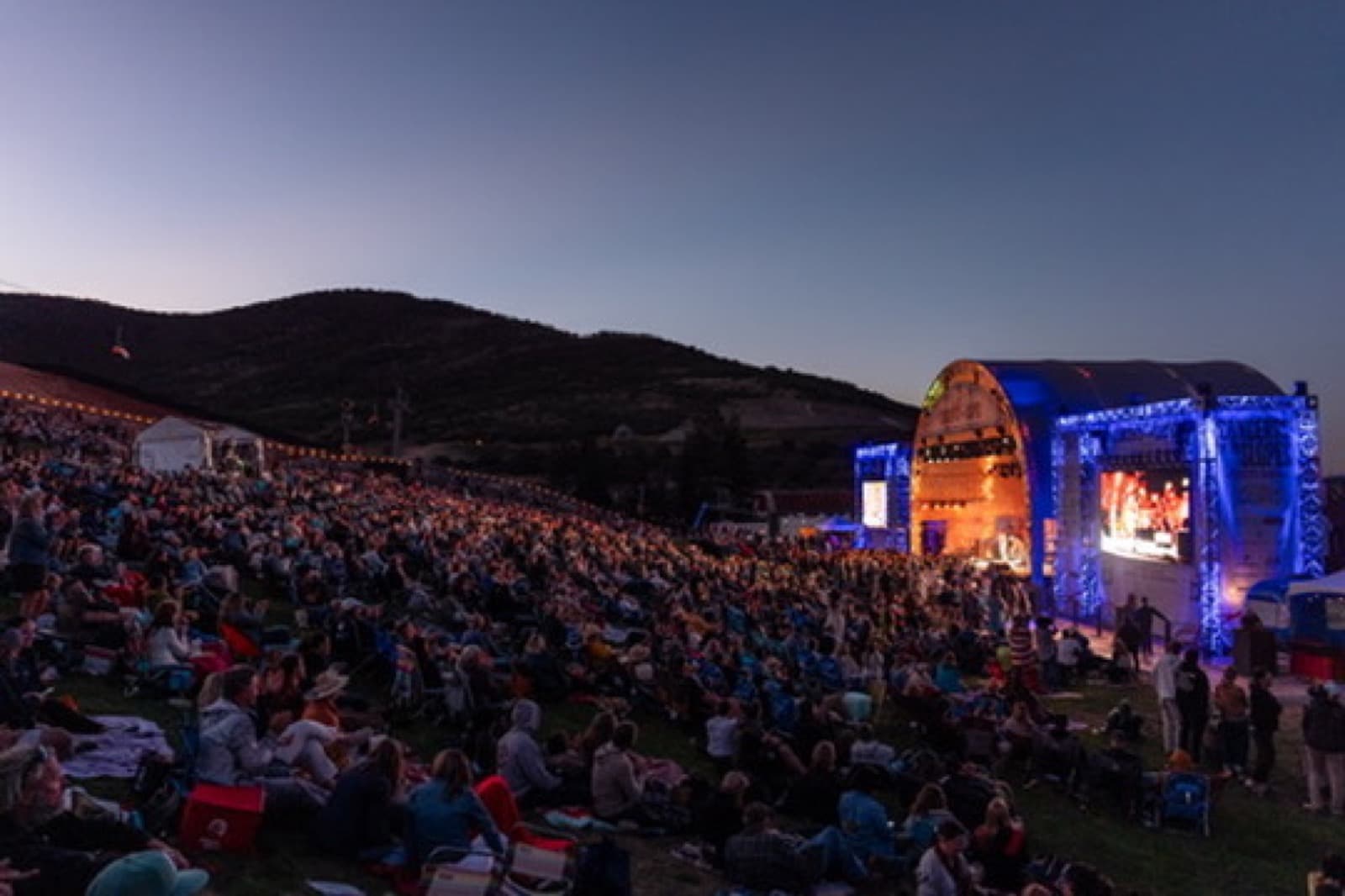Concert on the Slopes stage and hillside crowd at dusk.