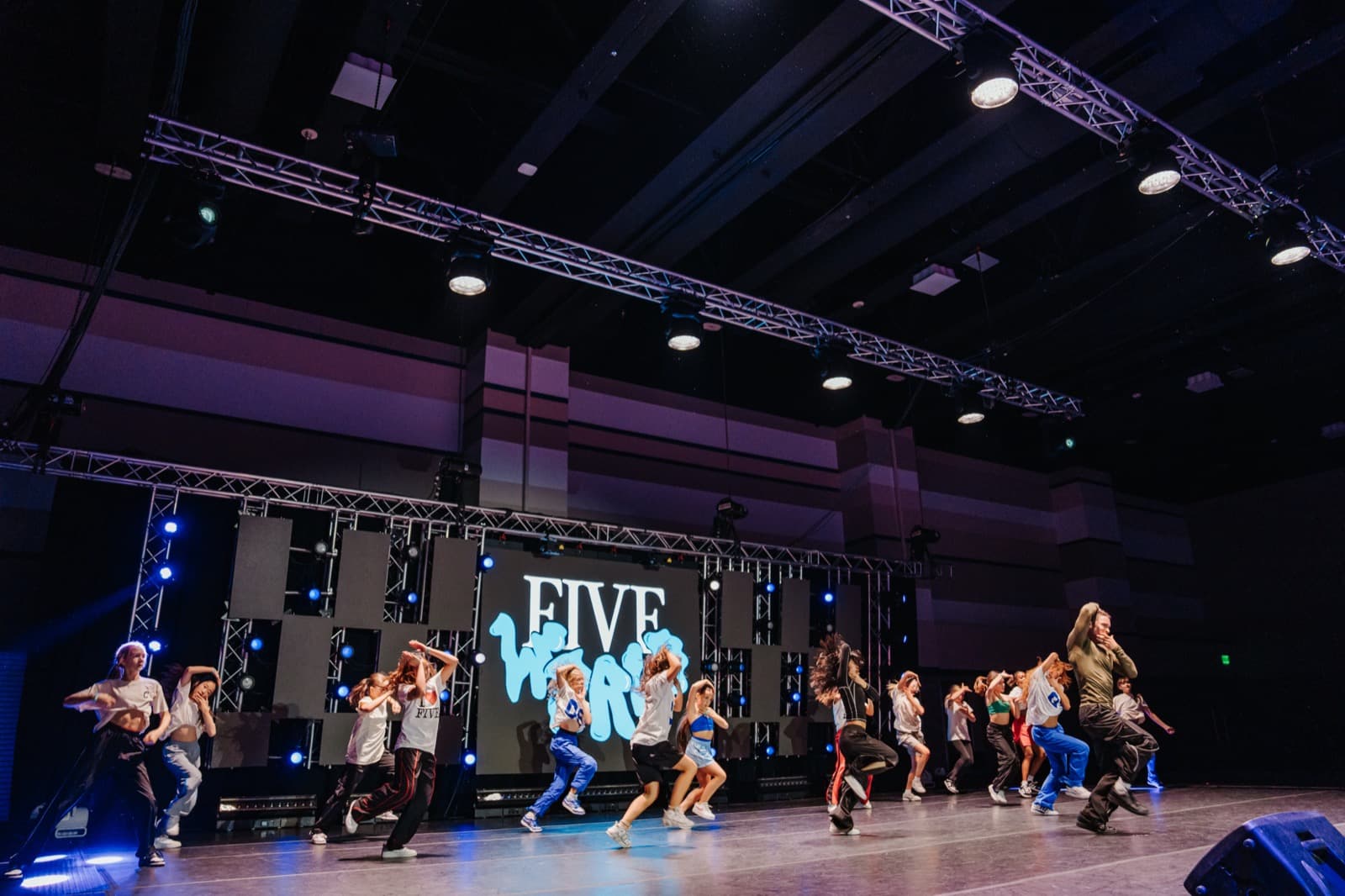 Five World stage with presenters and a large video wall in a production venue.