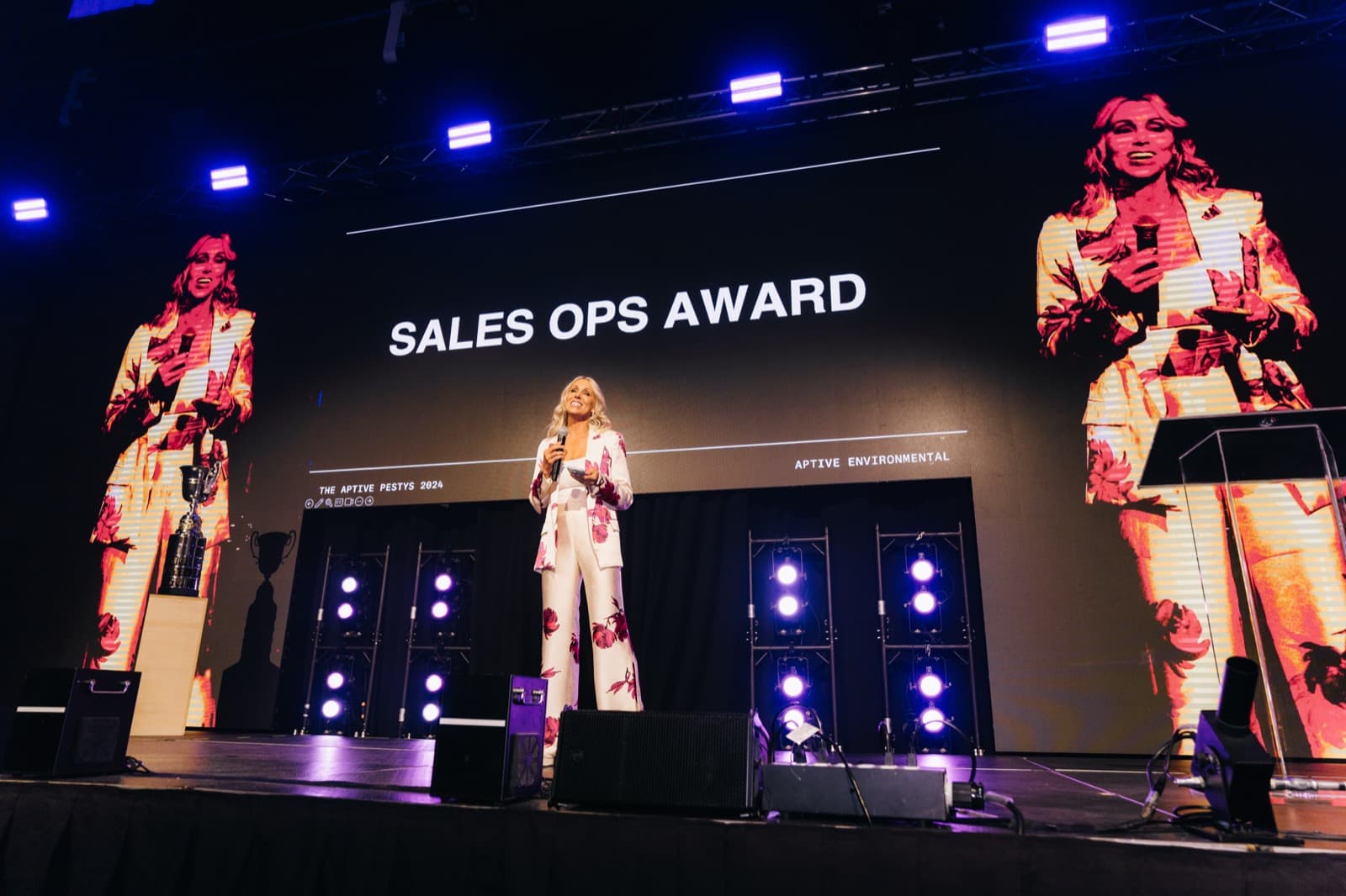 Aptive branded awards stage with presenters standing beneath a wide LED display.