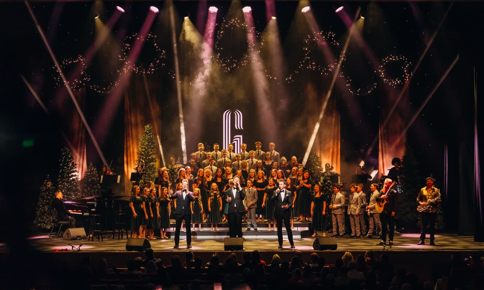Wide GENTRI stage view with warm overhead lights and a full ensemble.