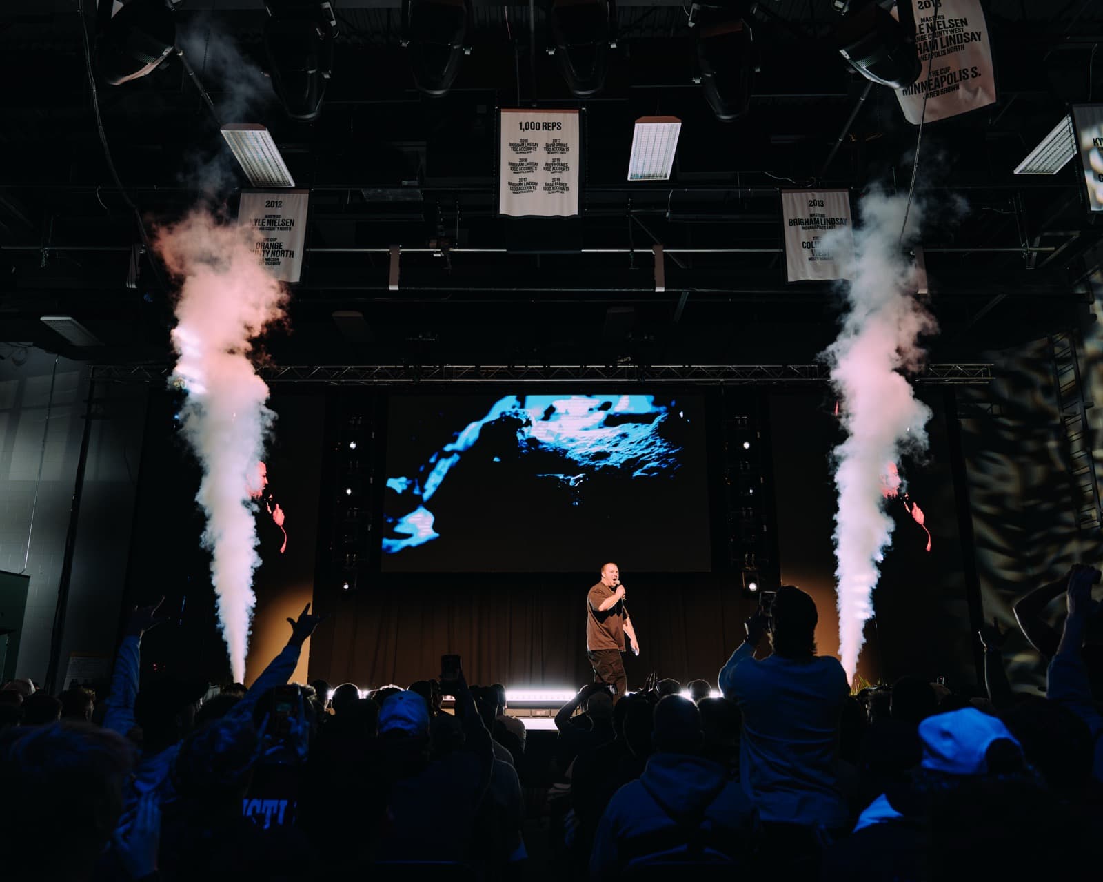 Aptive corporate presentation with a speaker on stage and company branding across the back wall.