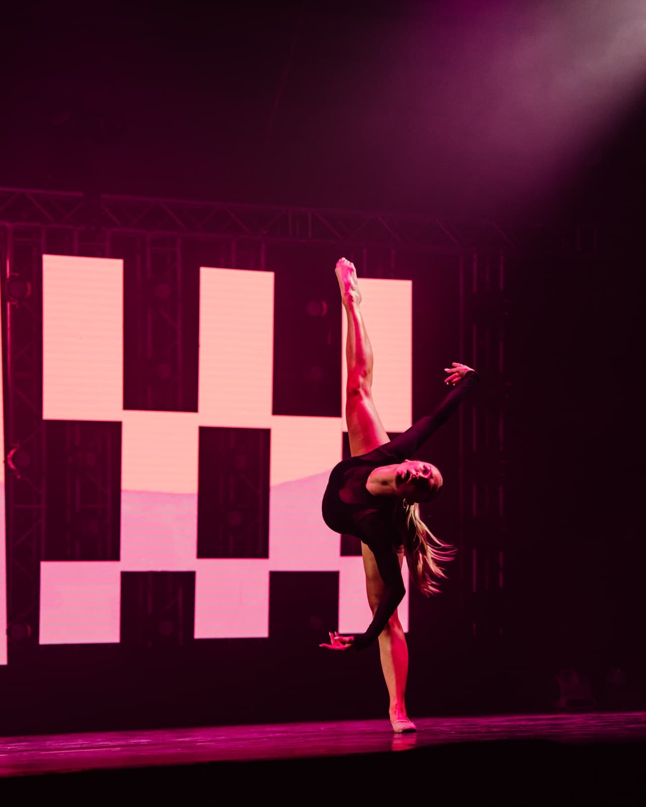 Five World performer silhouetted against bold pink LED graphics.