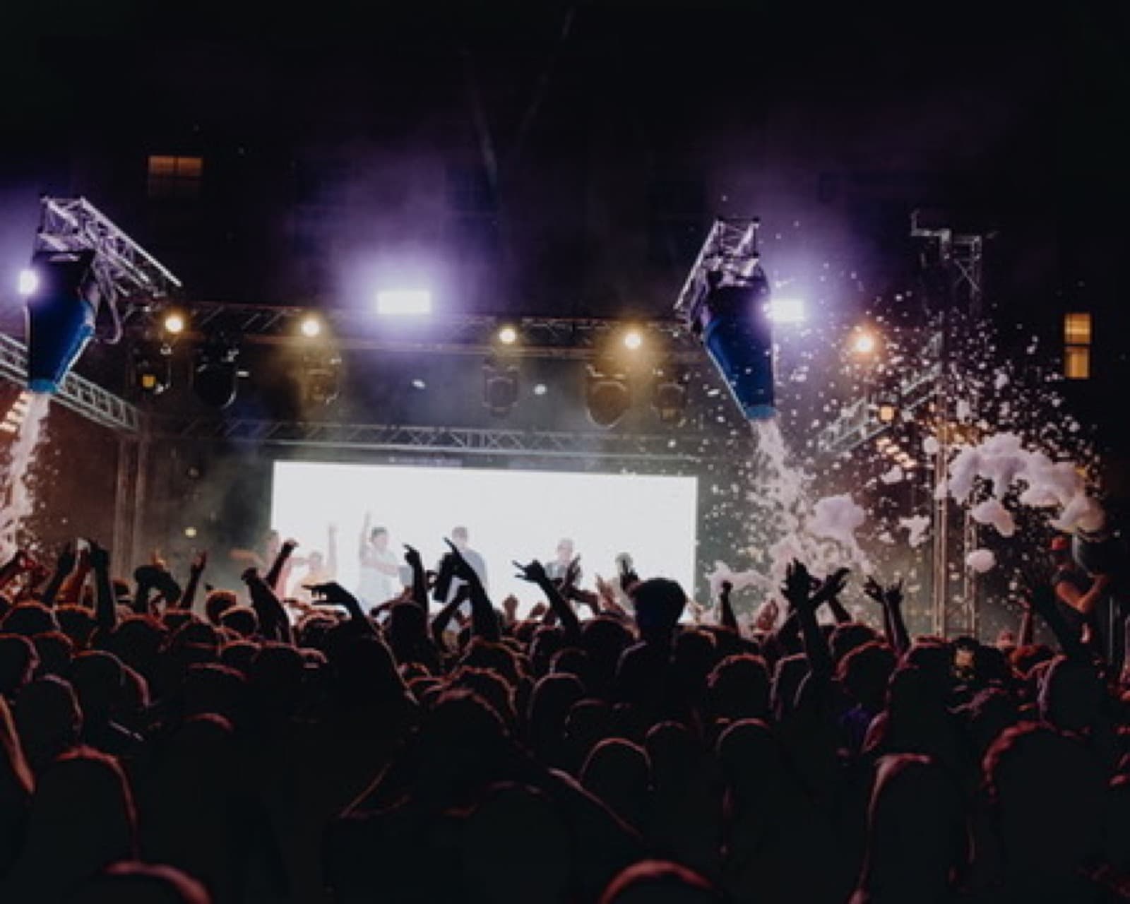 Private event dance floor with a bright stage and energetic audience.