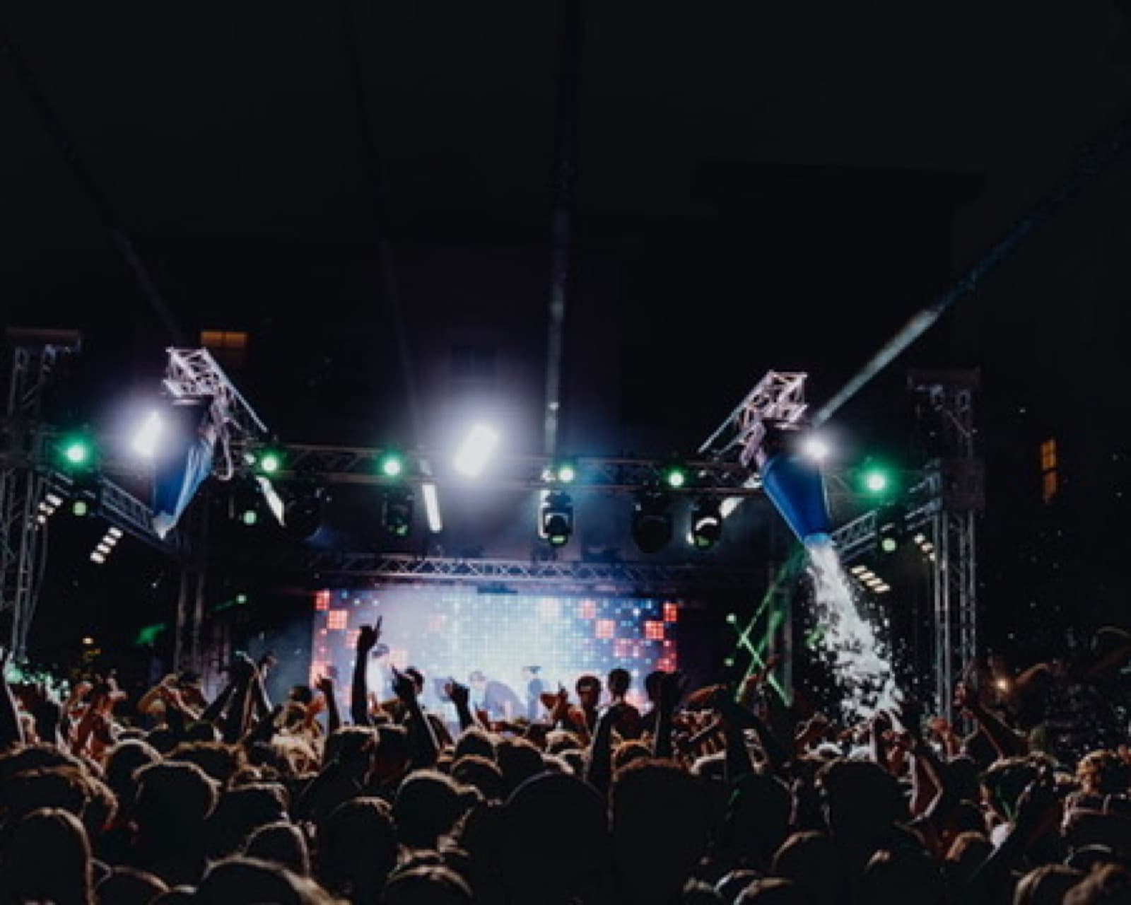 Blue and white stage lighting over a packed private party crowd.