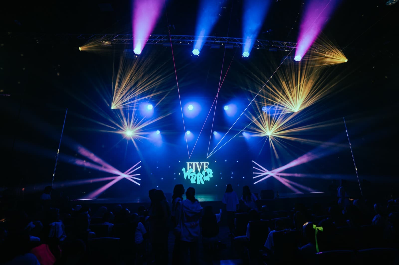 Five World stage lighting with blue beams sweeping across the venue.