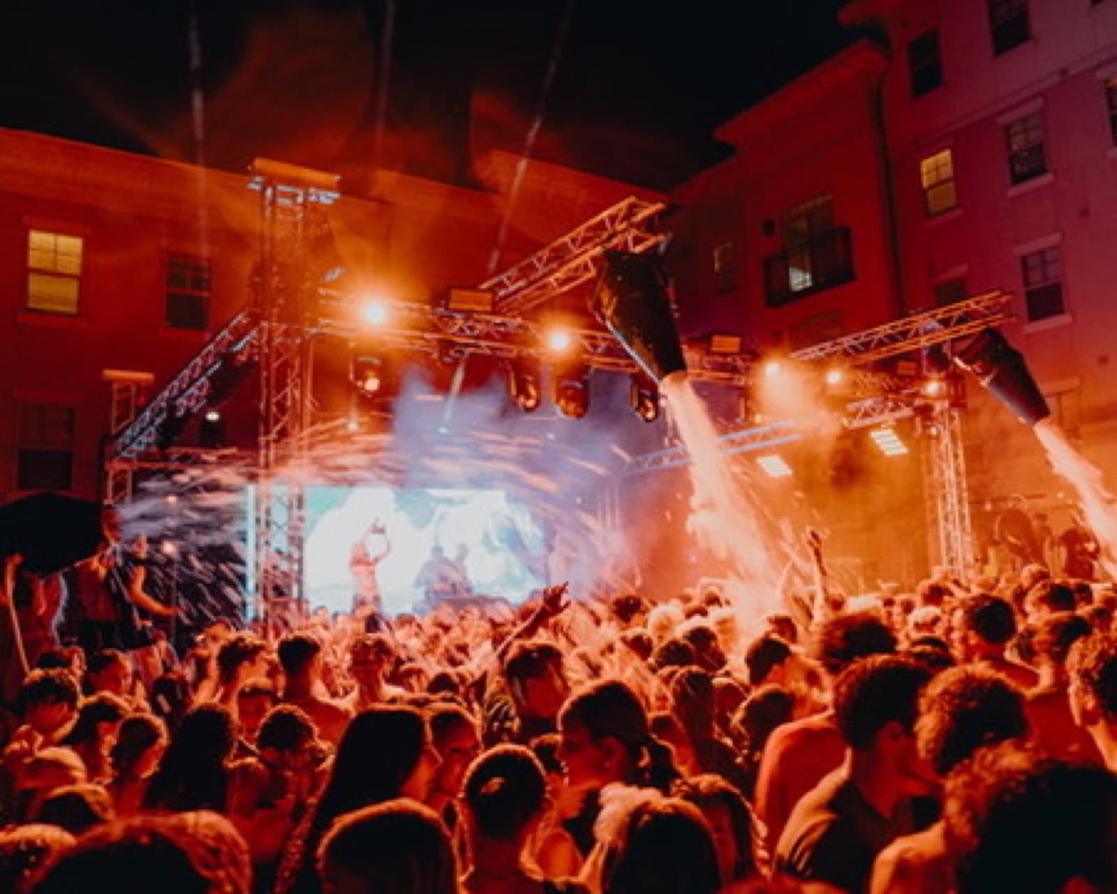 Orange and red lighting over a private event crowd with performers on stage.