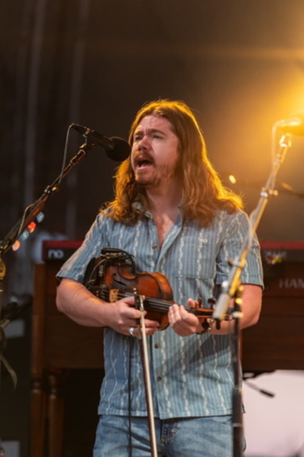 Lead singer with guitar performing in front of amber stage lights.