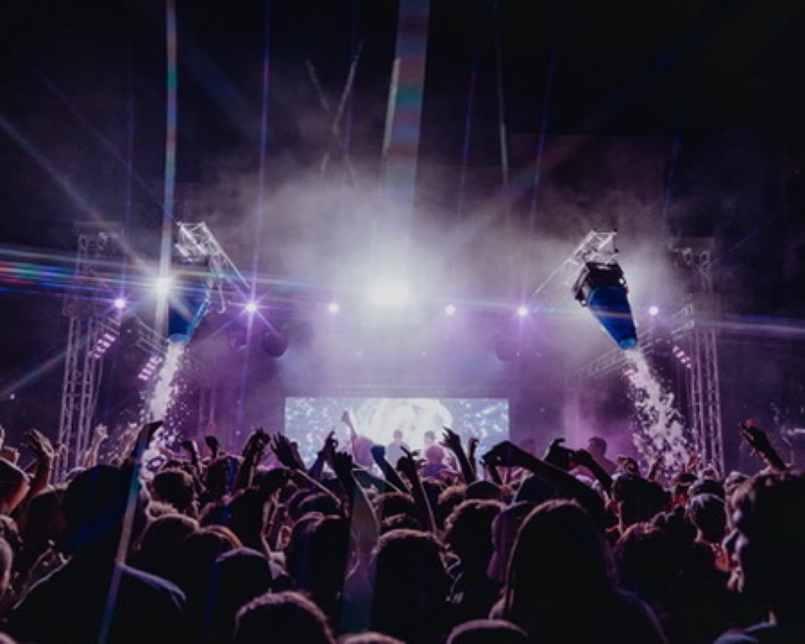 Purple and white lighting over dancers and a live party stage.