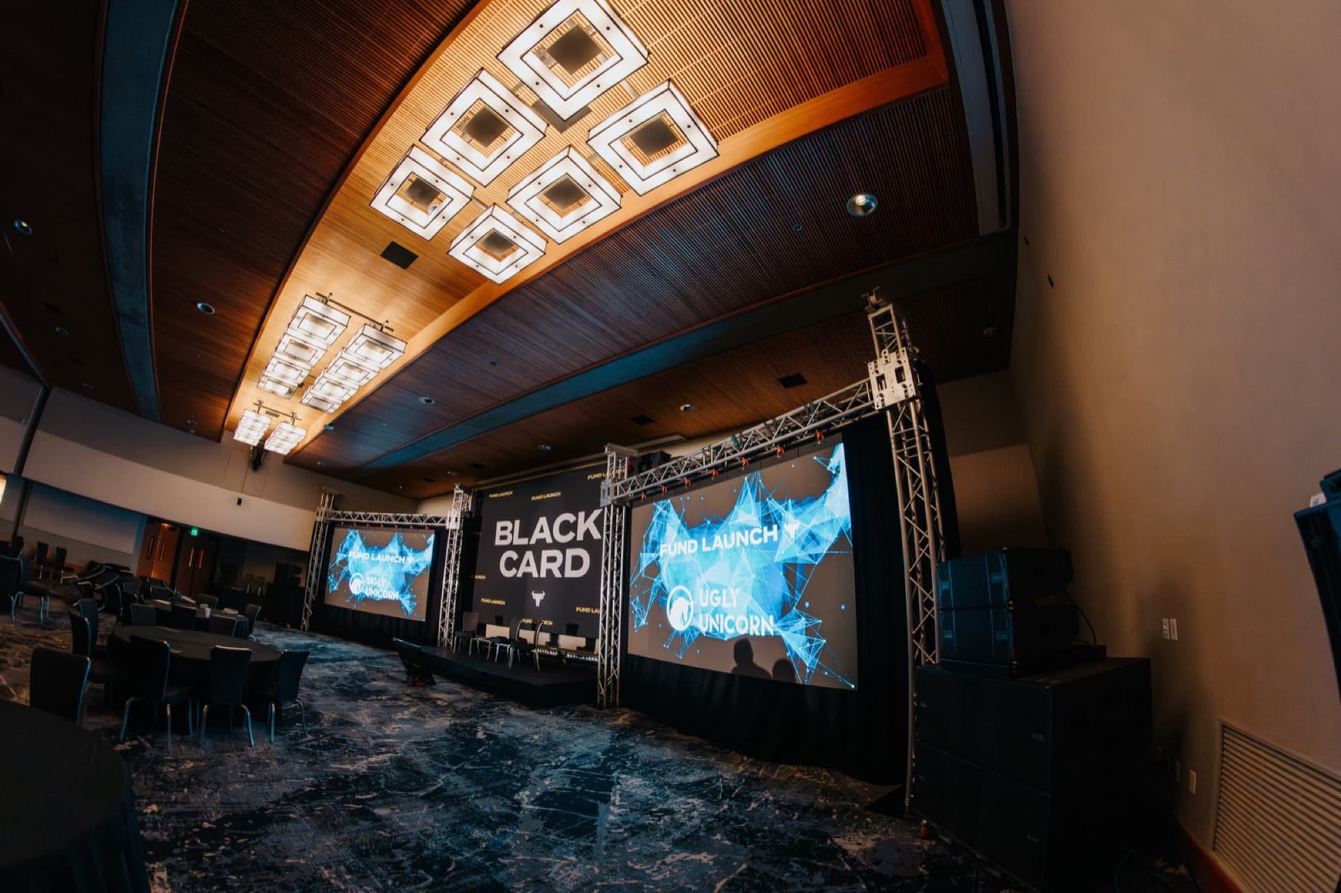 Black Card branded stage inside a theater with warm architectural lighting and a large screen.